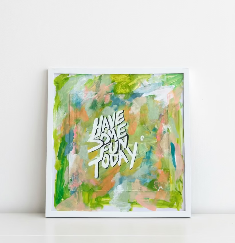 Framed abstract painting with colorful brushstrokes and text 'HAVE SOME FUN TODAY!' on a wooden surface.