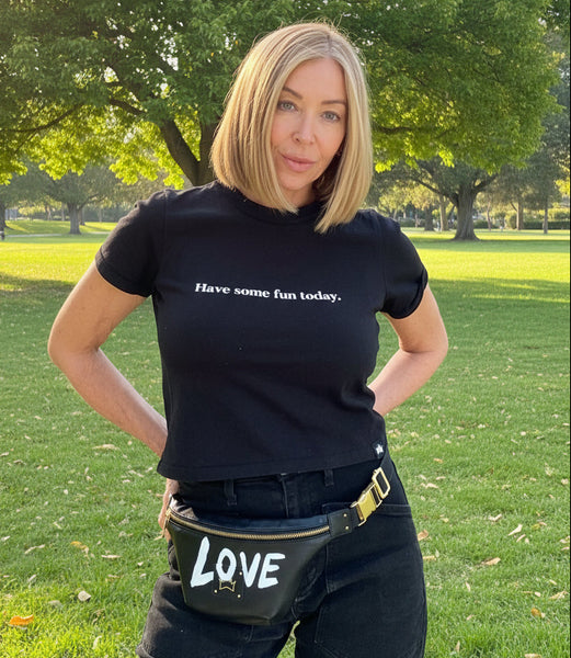 Person wearing a black t-shirt with text and a fanny pack in a room.