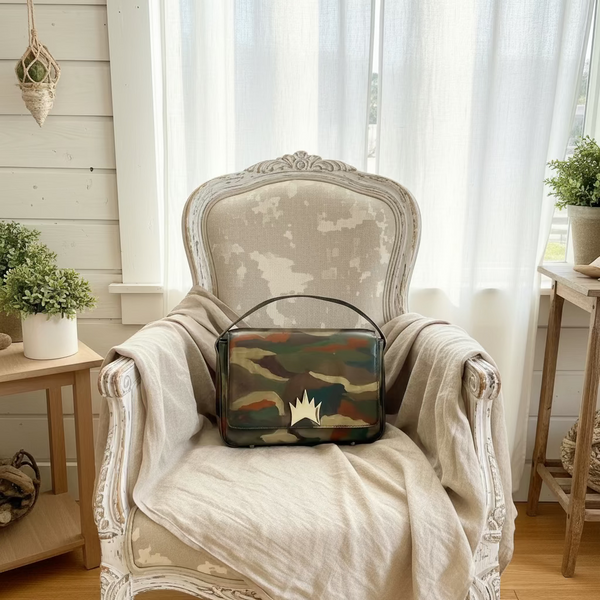 Camouflage-patterned handbag with a star design on a fluffy white surface.