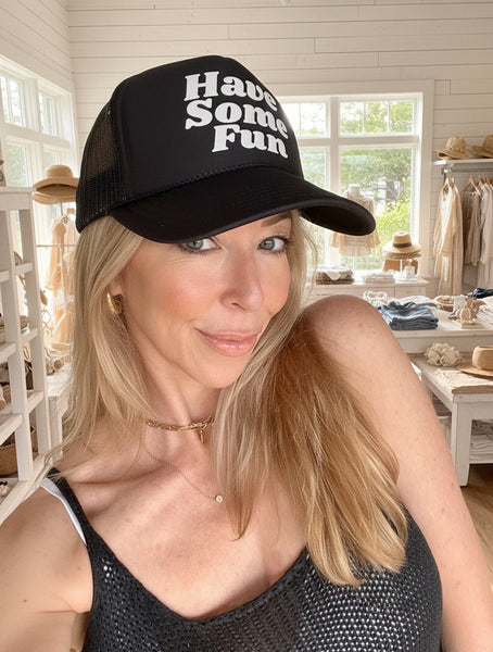A person wearing a black trucker hat with the text 'Have Some Fun' on it.