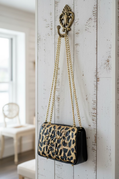 Leopard print handbag with gold chain on a fluffy white surface