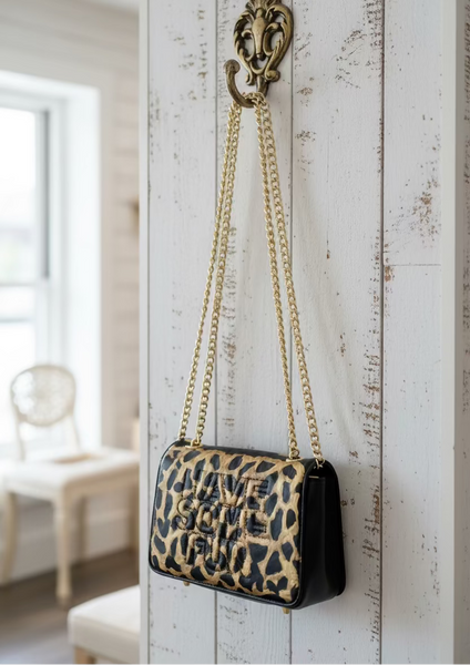 Leopard print handbag with gold chain on a fluffy white surface
