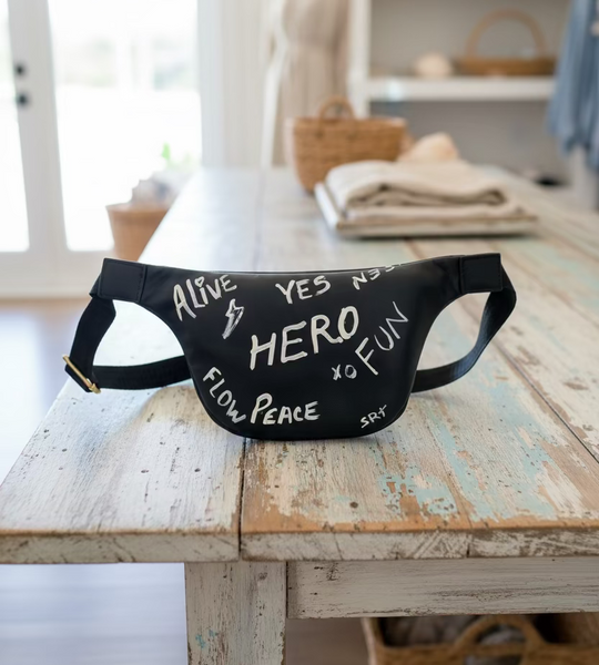 Black waist bag with text on a fluffy white surface