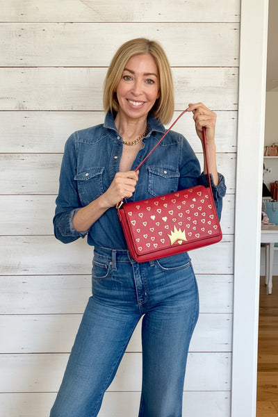 Woman holding a red handbag with a star design in a living room setting