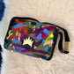 A rectangular shoulder bag with a glossy black frame and strap, featuring a vibrant multicolor abstract paint-splatter design on the front flap. The bag has a prominent gold crown logo on the center of the flap and is displayed on a white faux fur surface.